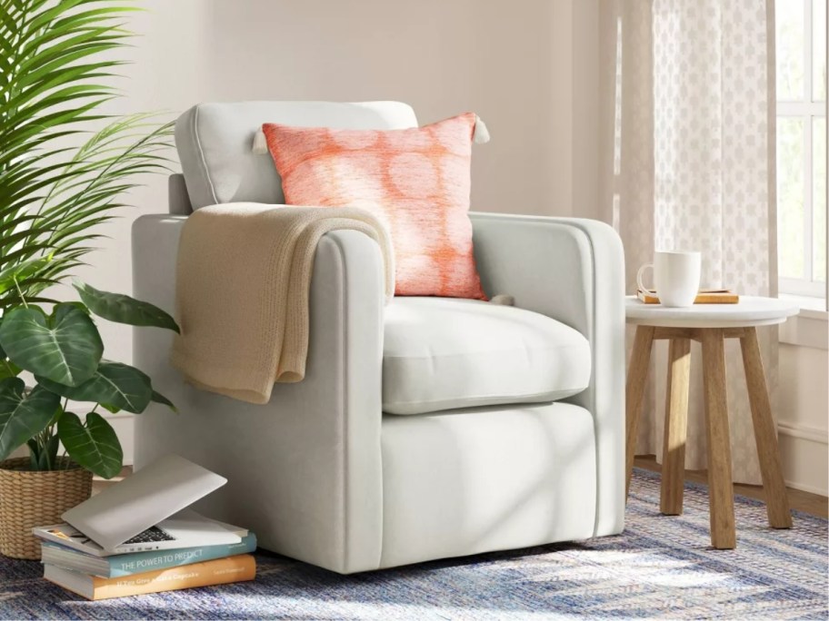 off white swivel chair with a throw pillow