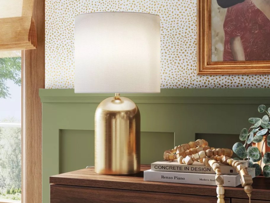 medium table lamp with gold base and white lid on a console table