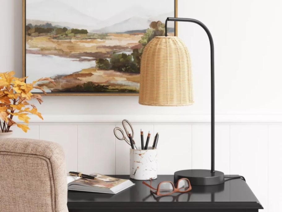 black arched table lamp with a rattan shade on a desk