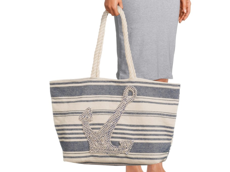 woman in gray dress holding white and blue striped beach tote