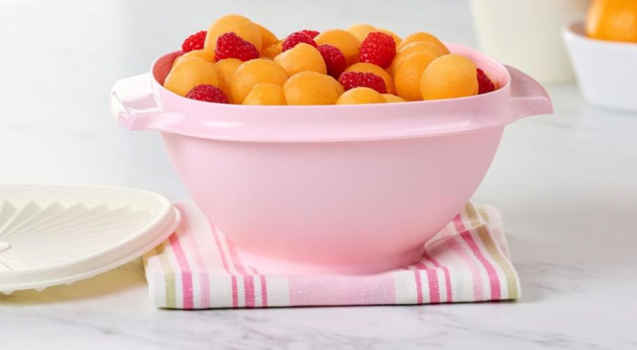 tupperware bowl in pale pink filled with cantelope and strawberries