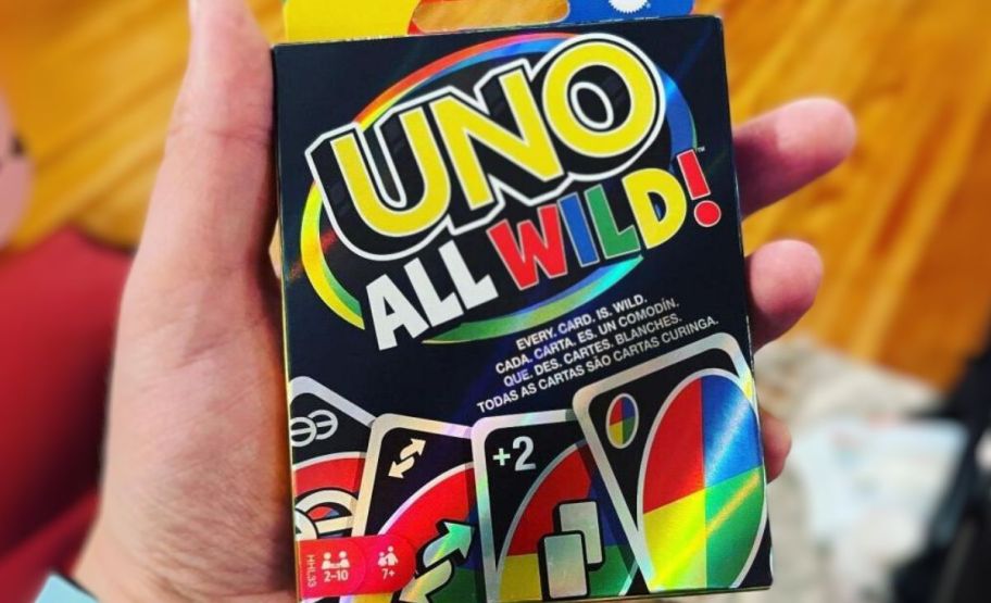 a mans hand holding a card pack of uno all wild