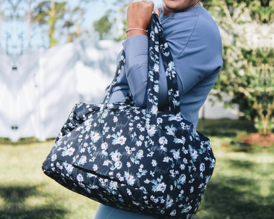 woman holding medium duffel bag in navy garden print