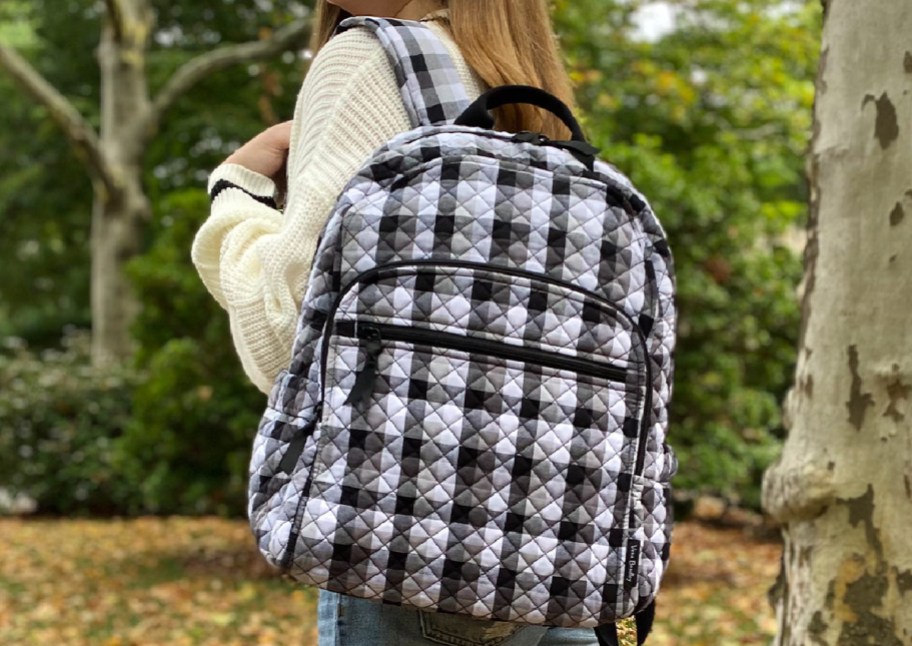 girl carrying black and white plaid backpack
