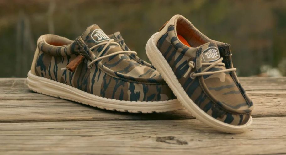 a pair of camo sneakers on a pier by a lake