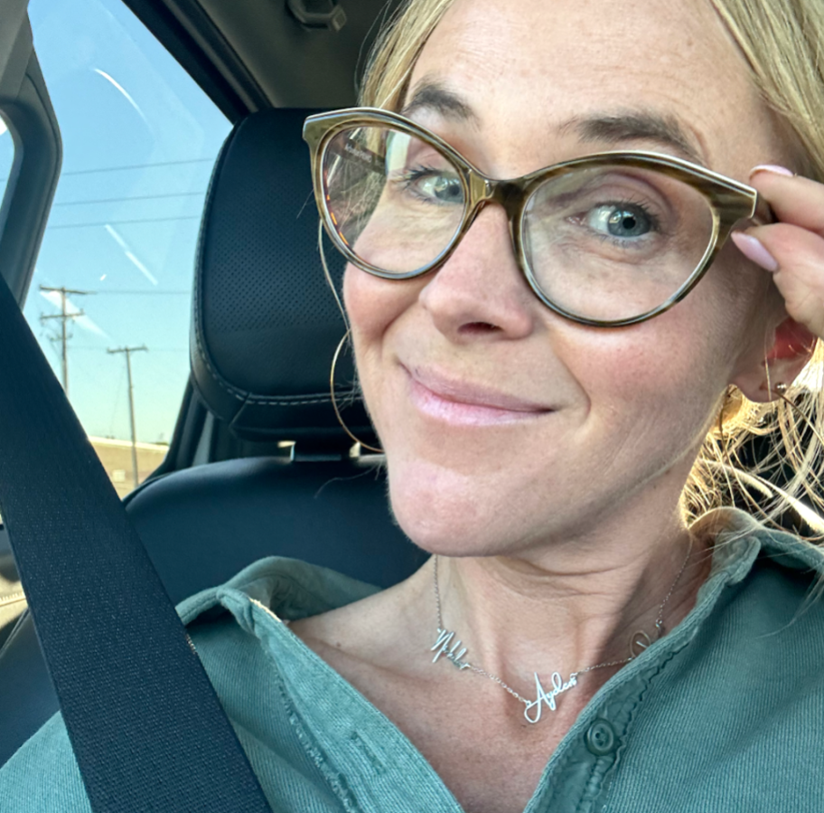 woman wearing name necklace and glasses in car 