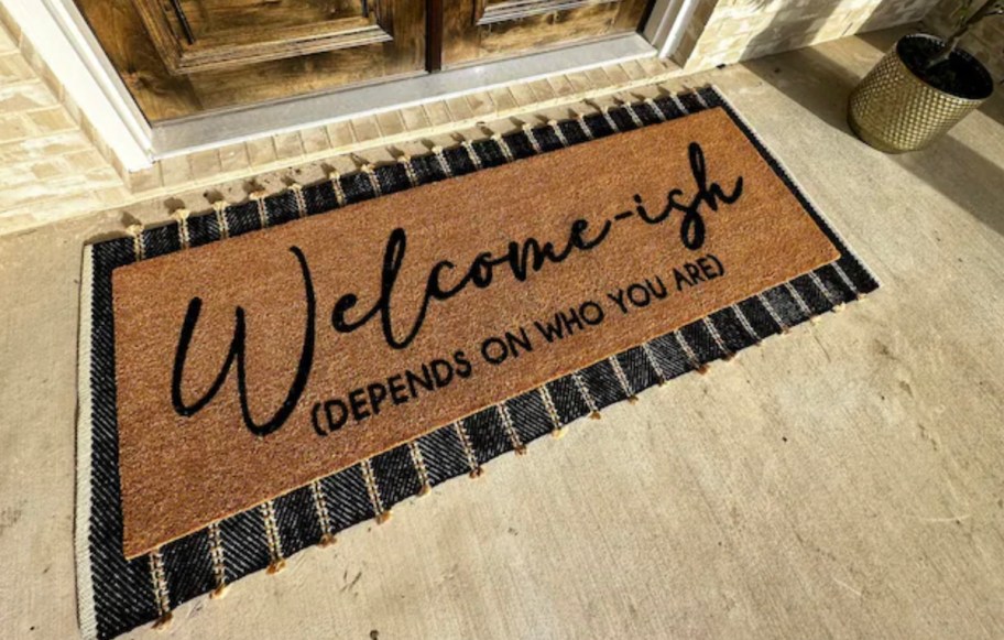 welcomeish depends on who you are funny doormat on stripe rug in front of wooden double doors