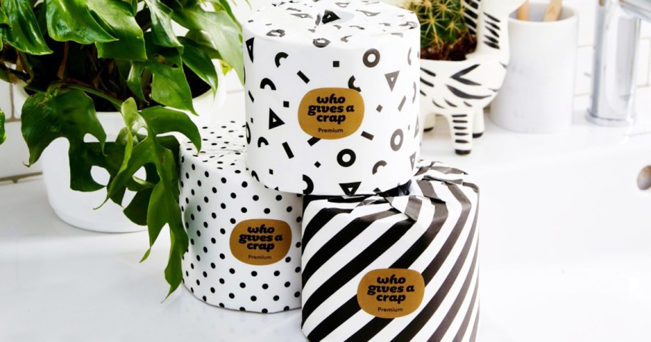 three black and white wrapped toilet paper rolls sitting on countertop