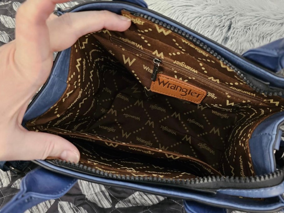 hand showing interior of blue wrangler purse 