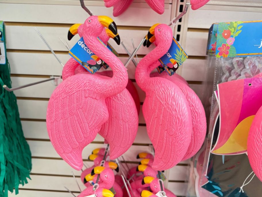 2 plastic pink flamingos hanging on a pegboard in store