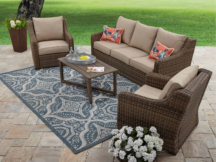 brown wicker outdoor patio furniture set on a rug on a patio