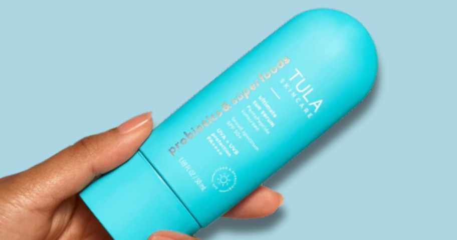 hand holding a blue color bottle of Tula sunscreen