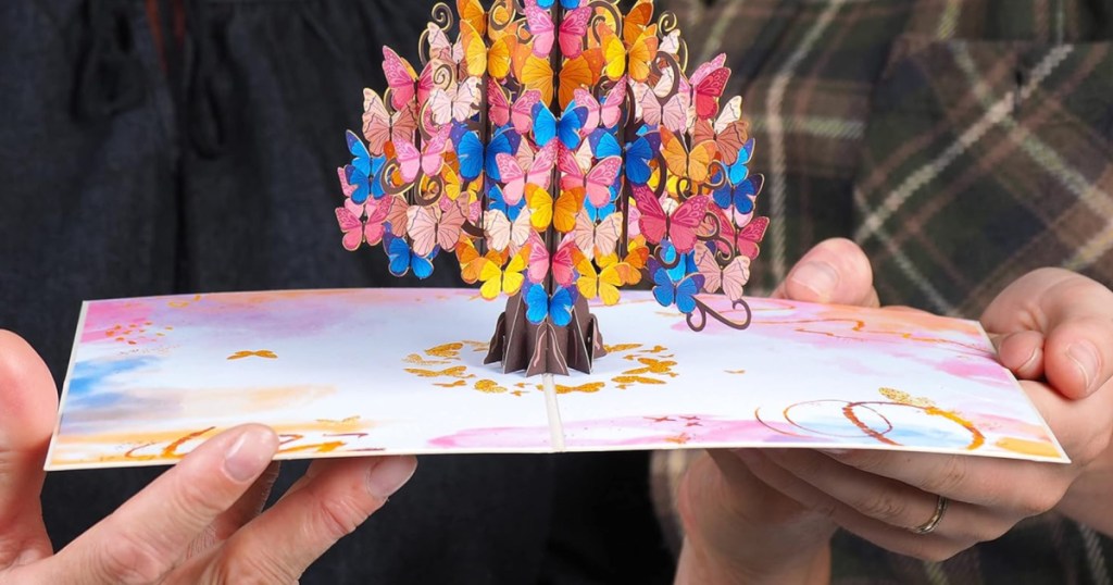 2 people holding up pop-up card featuring colorful tree