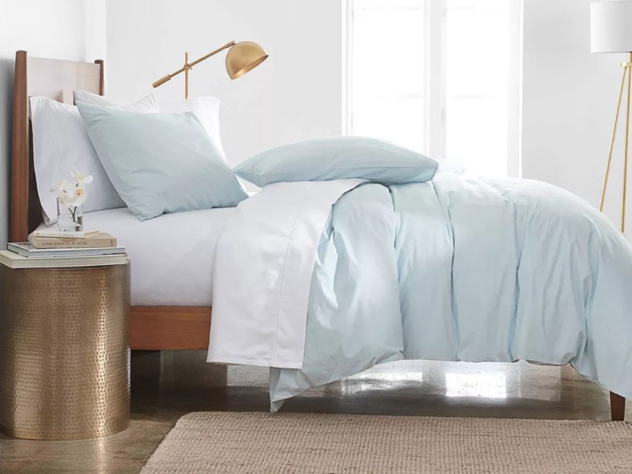 bed with light blue duvet cover and pillows and white sheets