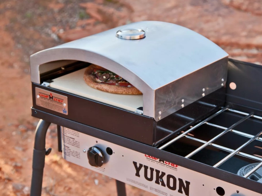pizza oven on top of an outdoor camp cooking stove