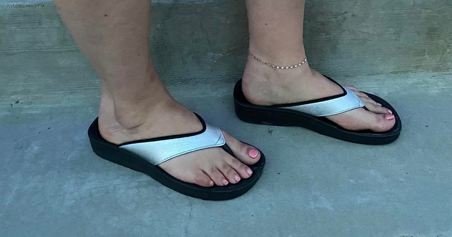 woman wearing silver flip flops