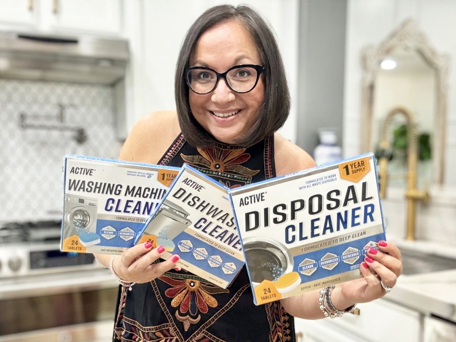 women holding up 3 boxes of Active Appliance Cleaners in kitchen