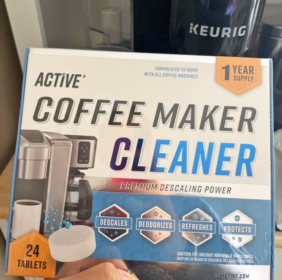 holding a box of Active Coffee Machine Cleaner in front of Keurig