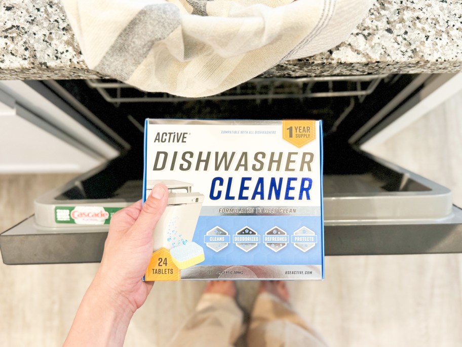 holding a box of Active Dishwasher Cleaner tablets in front of opened dishwasher