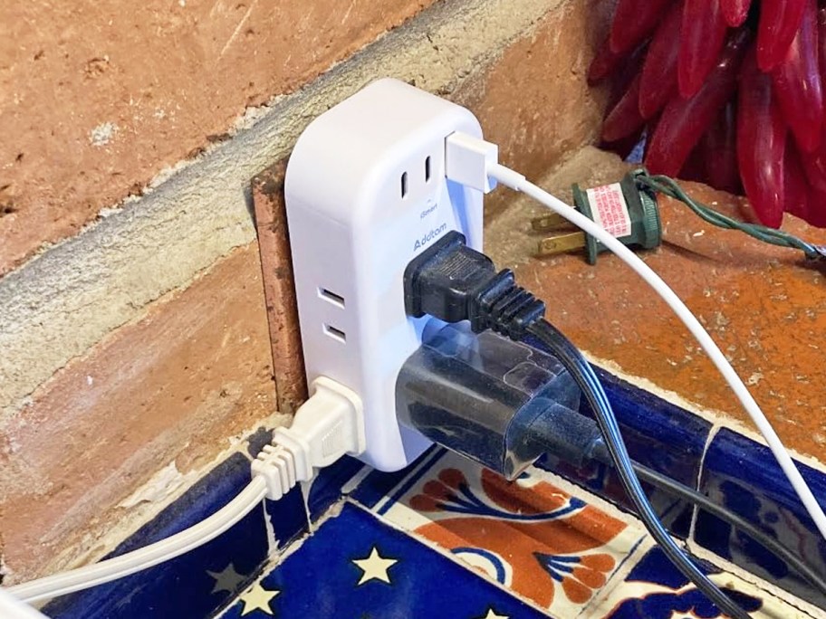 multiple plugs plugged into white outlet extender on counter