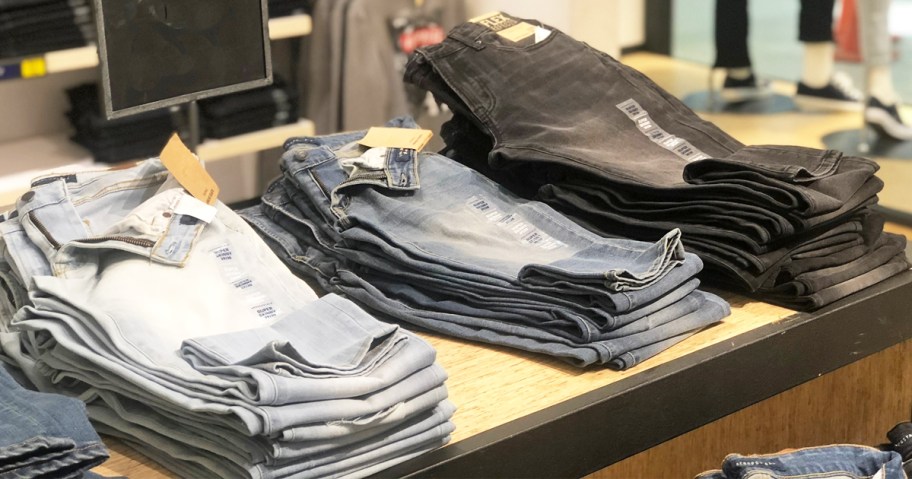 folded pairs of jeans in various washes on store display table