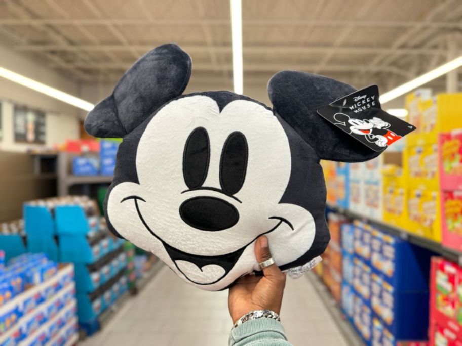 A person holding a Disney Mickey Face Pillow up in a store
