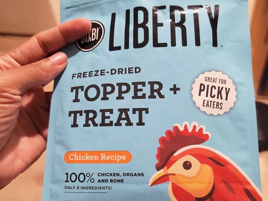 hand holding a blue bag of BIXBI Liberty Freeze Dried Dog Food Topper