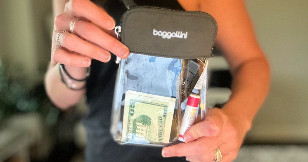 woman holding clear crossbody bag filled with money and lip balm