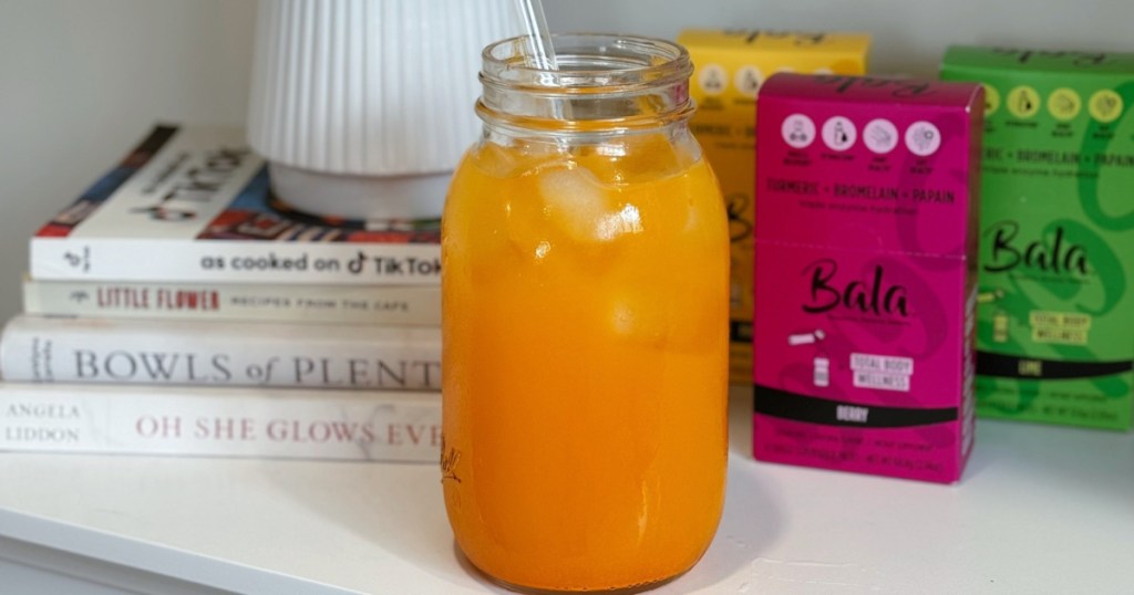 mason jar with orange liquid on table next to bala drink mixes