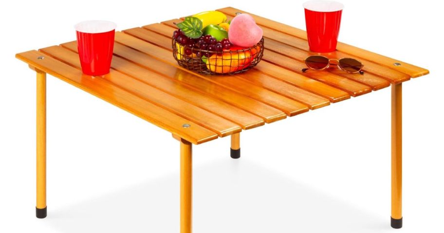 A small wooden table with cups and food upon it