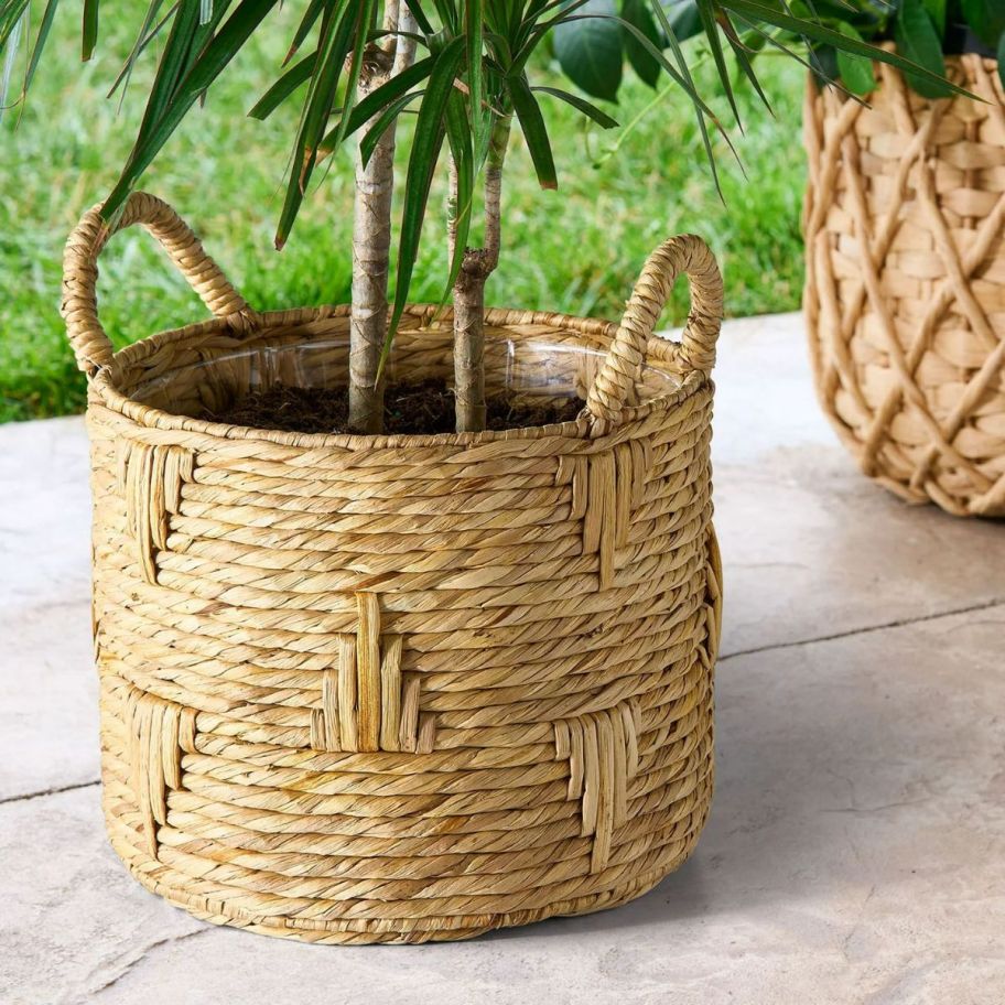 a round bulrush basket planter on a patio with a plant in it