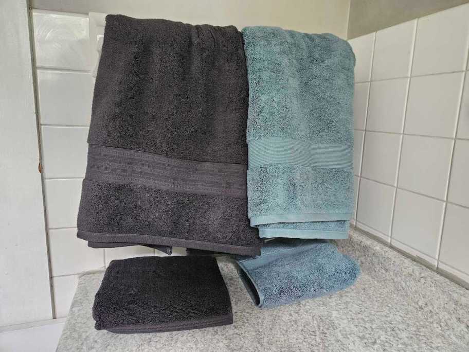 dark gray and blue bath towels hanging on drying rod in bathroom