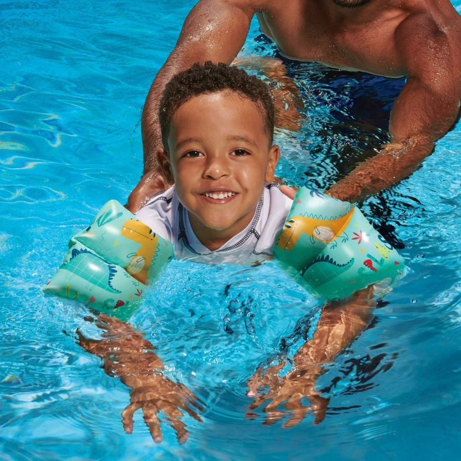 a little boy in a pool wearing water wings