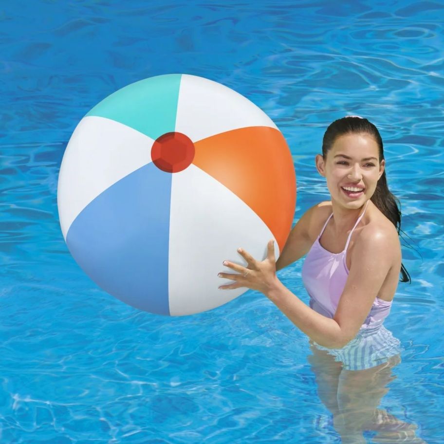 a girl in a pool with a giant beach ball