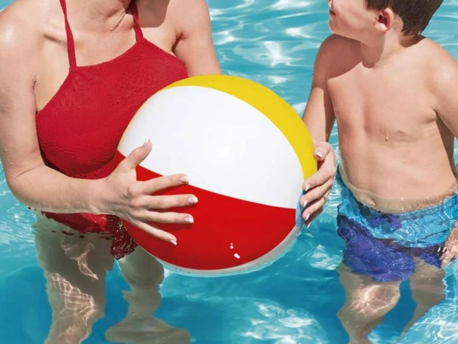 A woman and a boy holding a beach ball in a pool