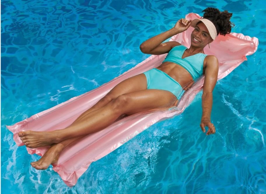 a woman on a pink inflatable swim raft in a pool