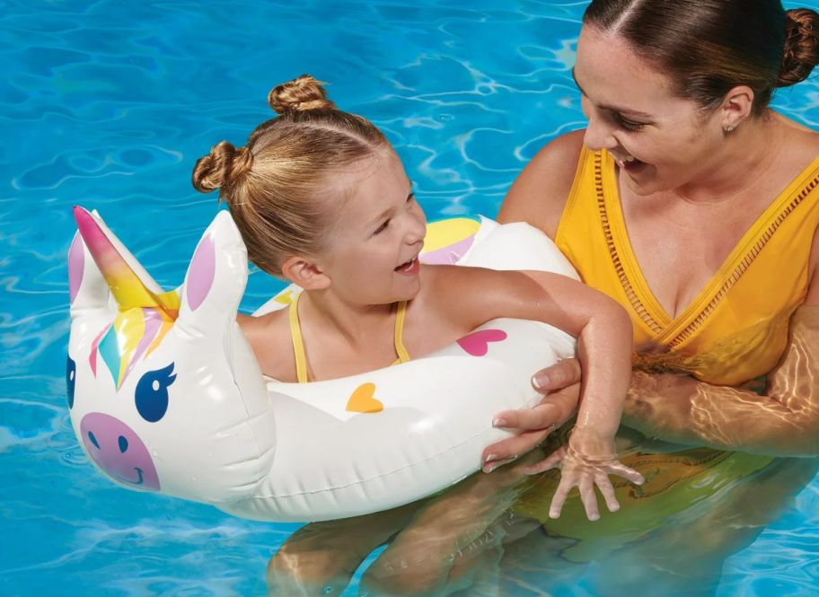 a little girl in a pool in a unicorn swim ring