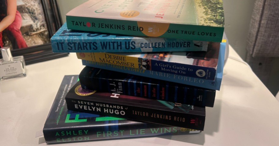 stack of books on white nightstand