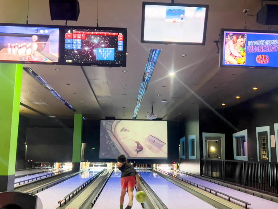 Child playing at a bowling aisle with the screens on