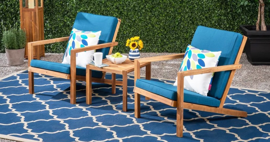 two wood patio chairs with bright blue cushions and matching side table