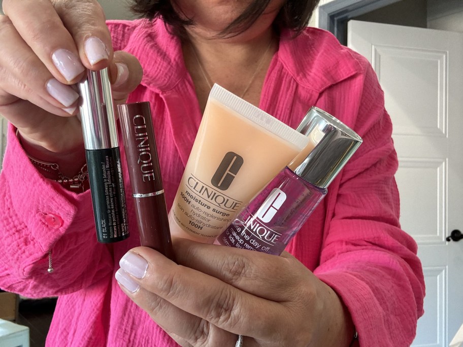 woman in pink shirt holding up clinique products