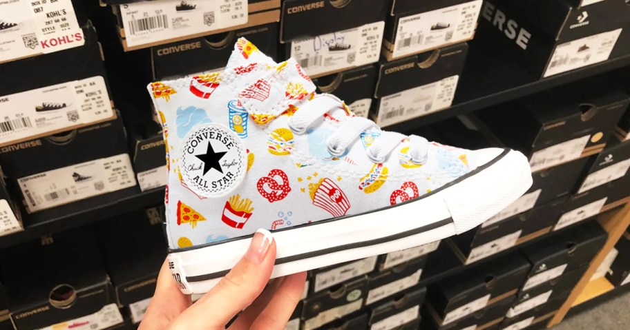 hand holding up a converse sneaker with snacks print