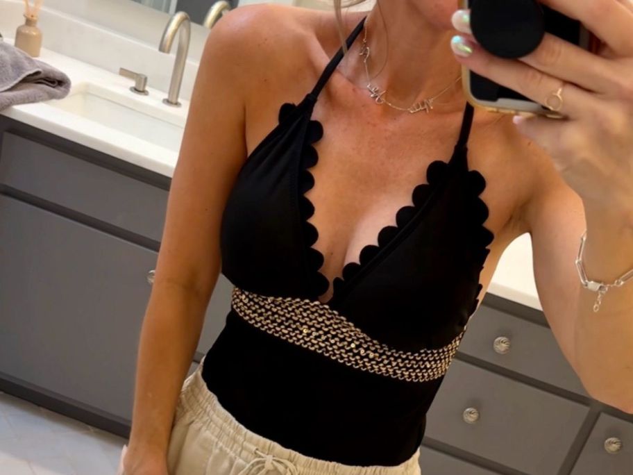 A woman wearing a Cupshe Gold Contrast-Stitching Scalloped Halter One Piece Swimsuit in the bathroom