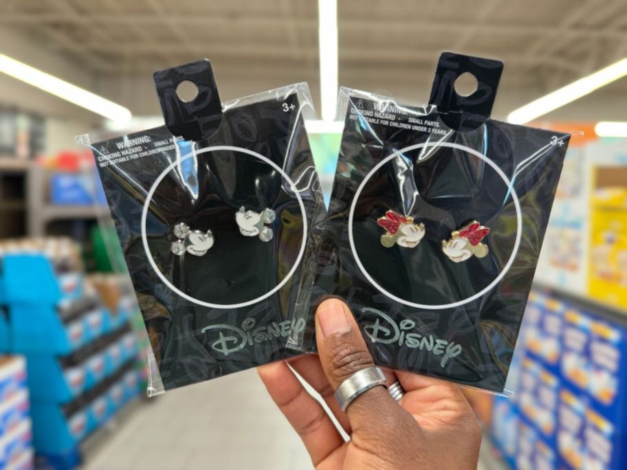 A hand holding 2 pair of Disney Character Earrings