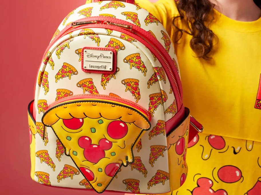 woman holding up a pizza print loungefly backpack