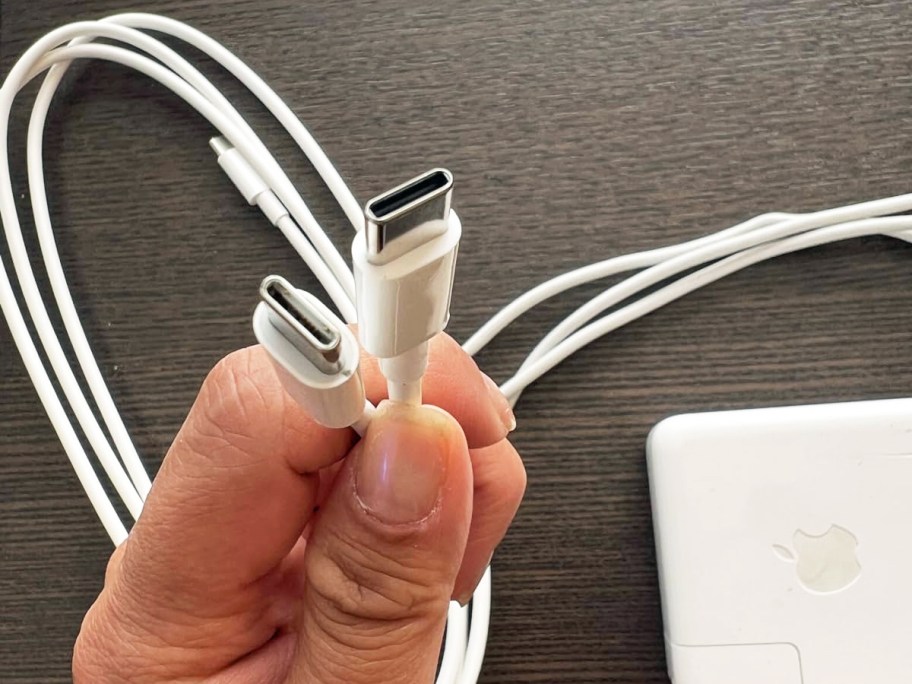 hand holding two white usb-c charging cables