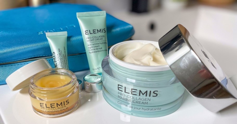 ELEMIS Super-Size Pro-Collagen Marine Cream and other ELEMIS skincare products on a bathroom counter with a blue cosmetic bag