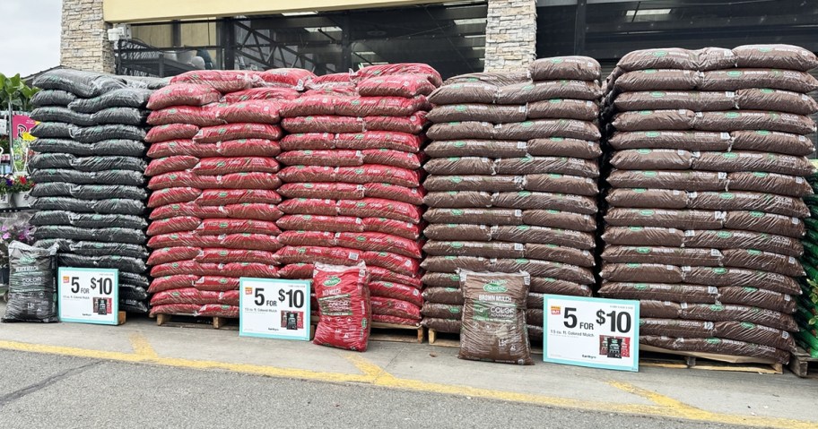 palettes of black, red, and brown wood mulch in front of home depot store