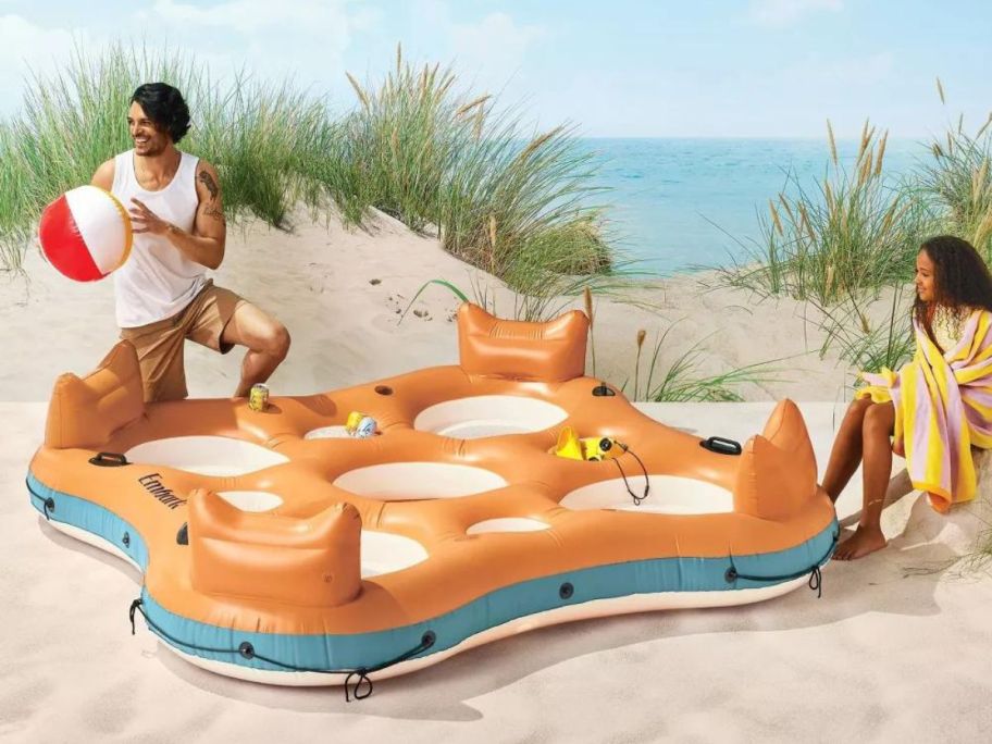 Embark 4-Person Orange Float on beach with 2 people beside it