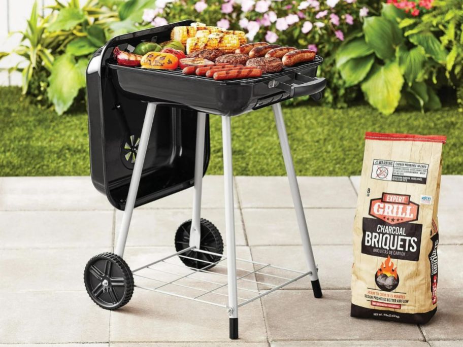 A small, square grill with wheels on a patio